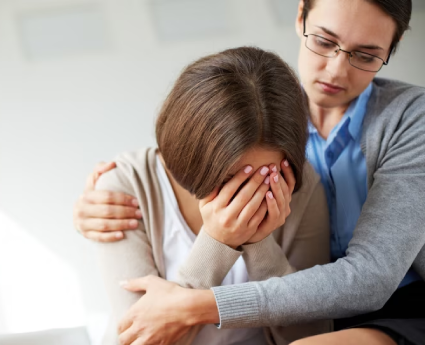 A woman sitting next to another person holding her head.