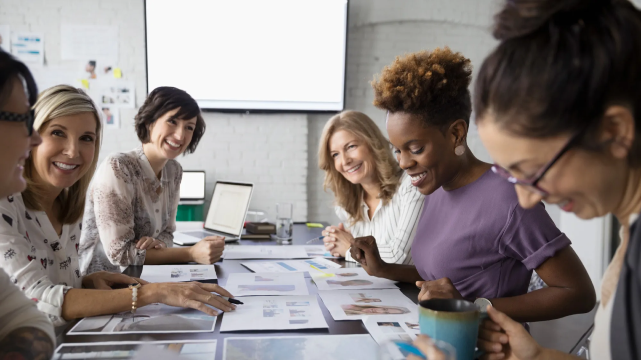 A group of women sitting at a table with papers.